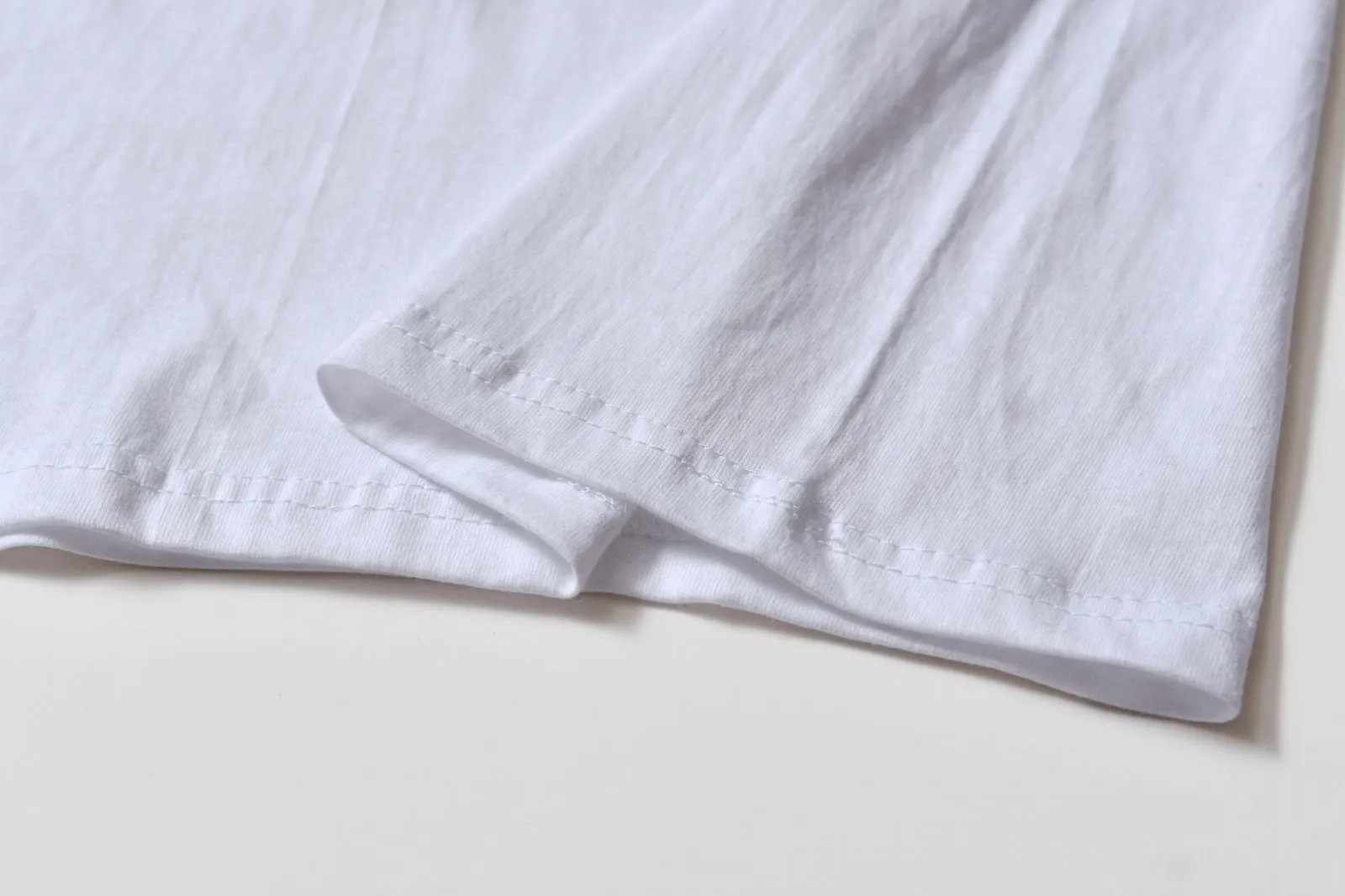 White cotton pullover overalls with short sleeves and a round neck, shown on a hanger.