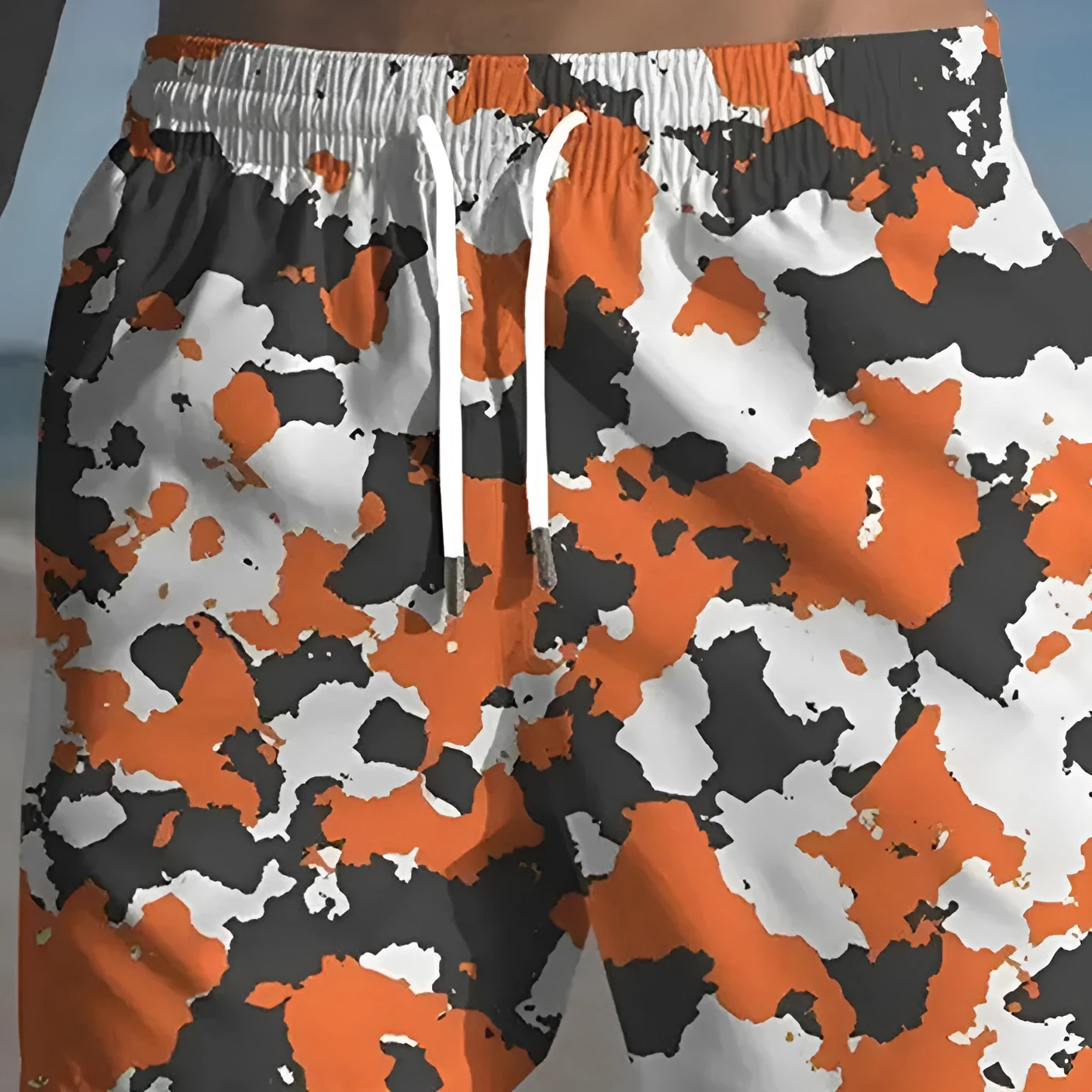 Men's printed polyester beach shorts on a model, showing elastic waistband and casual fit.