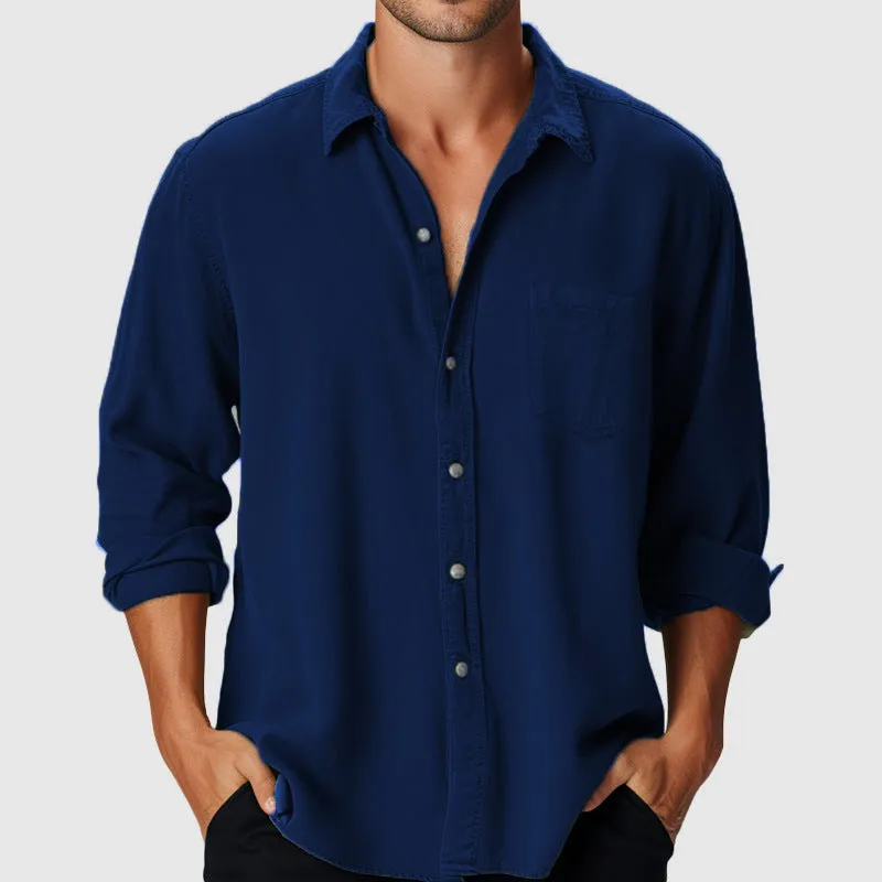 Man wearing a loose-fit blue casual shirt with a stand collar and long sleeves on a beach.