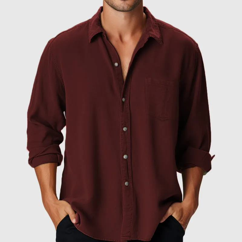 Man wearing a loose-fit blue casual shirt with a stand collar and long sleeves on a beach.