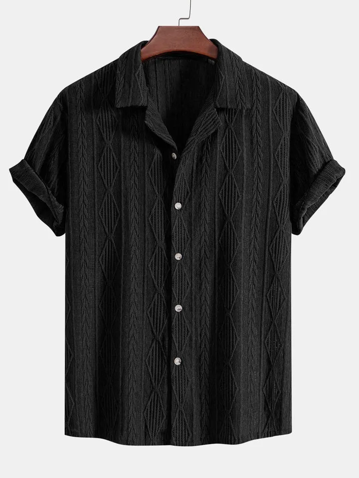 A man wearing a loose fit black short sleeve casual cardigan shirt on a beach.