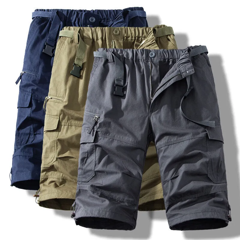Men's cotton cropped overalls in army green, shown in a casual summer setting.