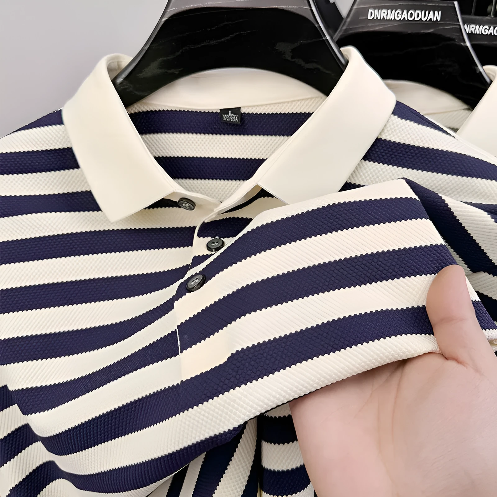 Men's black lapel jacquard stripes short-sleeve shirt on a hanger, showing asymmetrical design.
