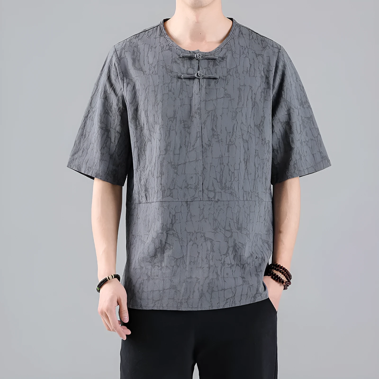 Man wearing a black loose-fit linen t-shirt with a retro jacquard pattern and fastener decoration.