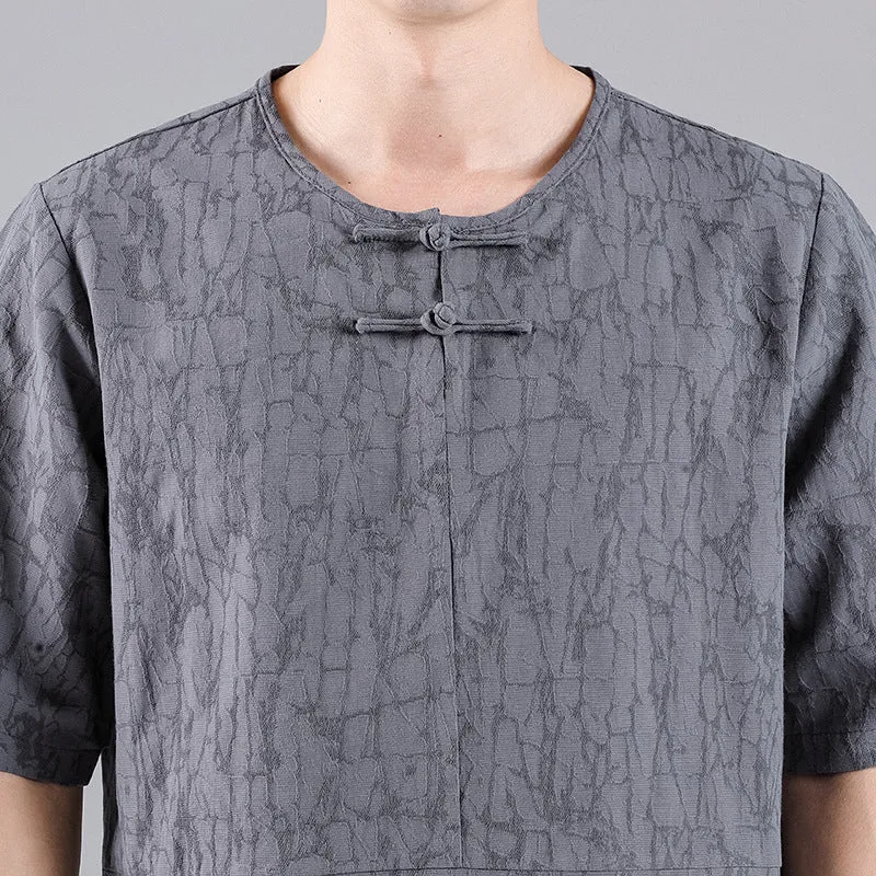 Man wearing a black loose-fit linen t-shirt with a retro jacquard pattern and fastener decoration.