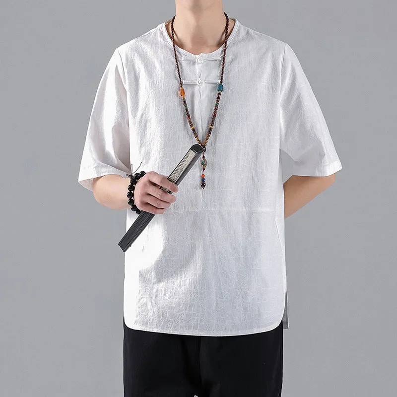 Man wearing a black loose-fit linen t-shirt with a retro jacquard pattern and fastener decoration.