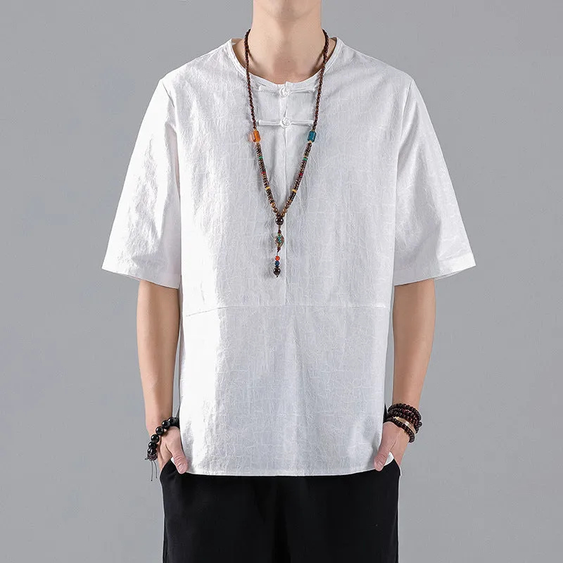 Man wearing a black loose-fit linen t-shirt with a retro jacquard pattern and fastener decoration.