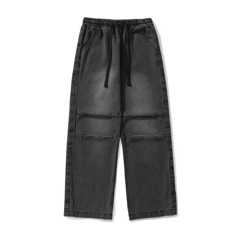 Pair of black pleated Japanese drawstring trousers lying flat showing loose-leg silhouette and drawstring waist
