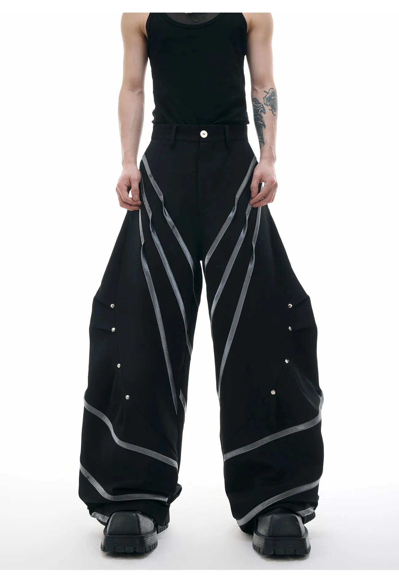 Men's black trousers with metal rivet stripes and pleated detail on the leg.