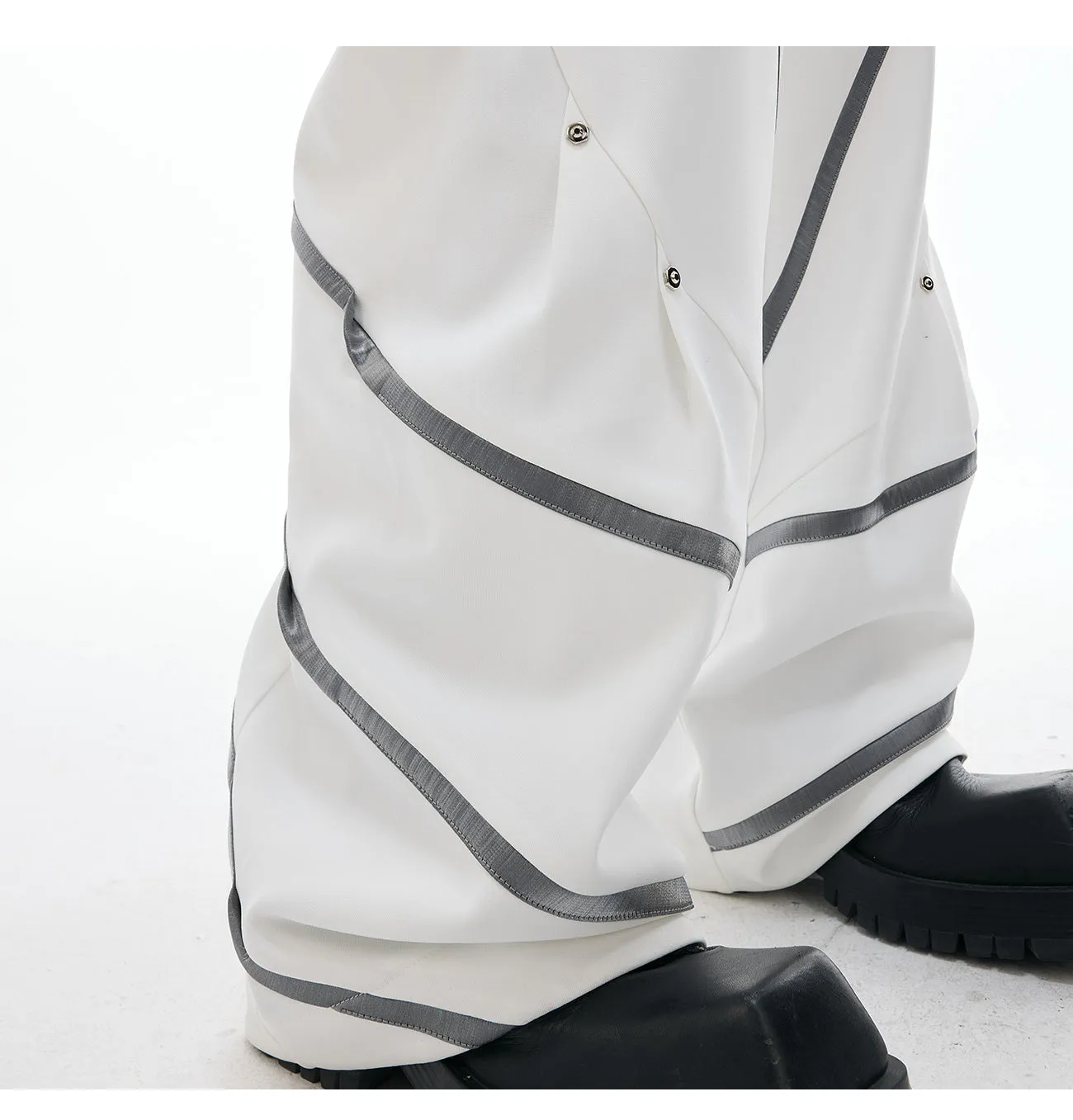 Men's black trousers with metal rivet stripes and pleated detail on the leg.