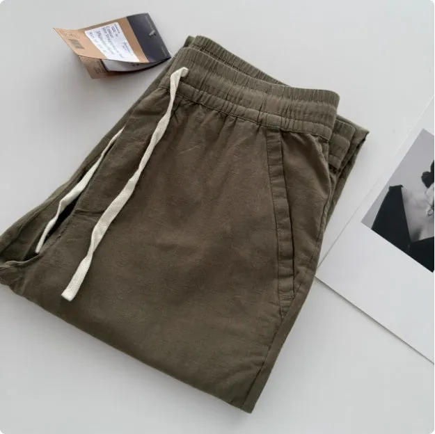 A man wearing beige loose straight-leg casual trousers with a drawstring waist.