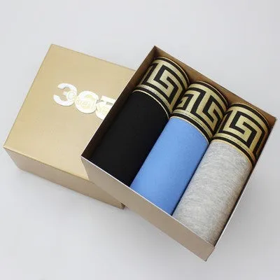 Three pairs of mens plain cotton boxer shorts in black, blue, and grey, folded together.