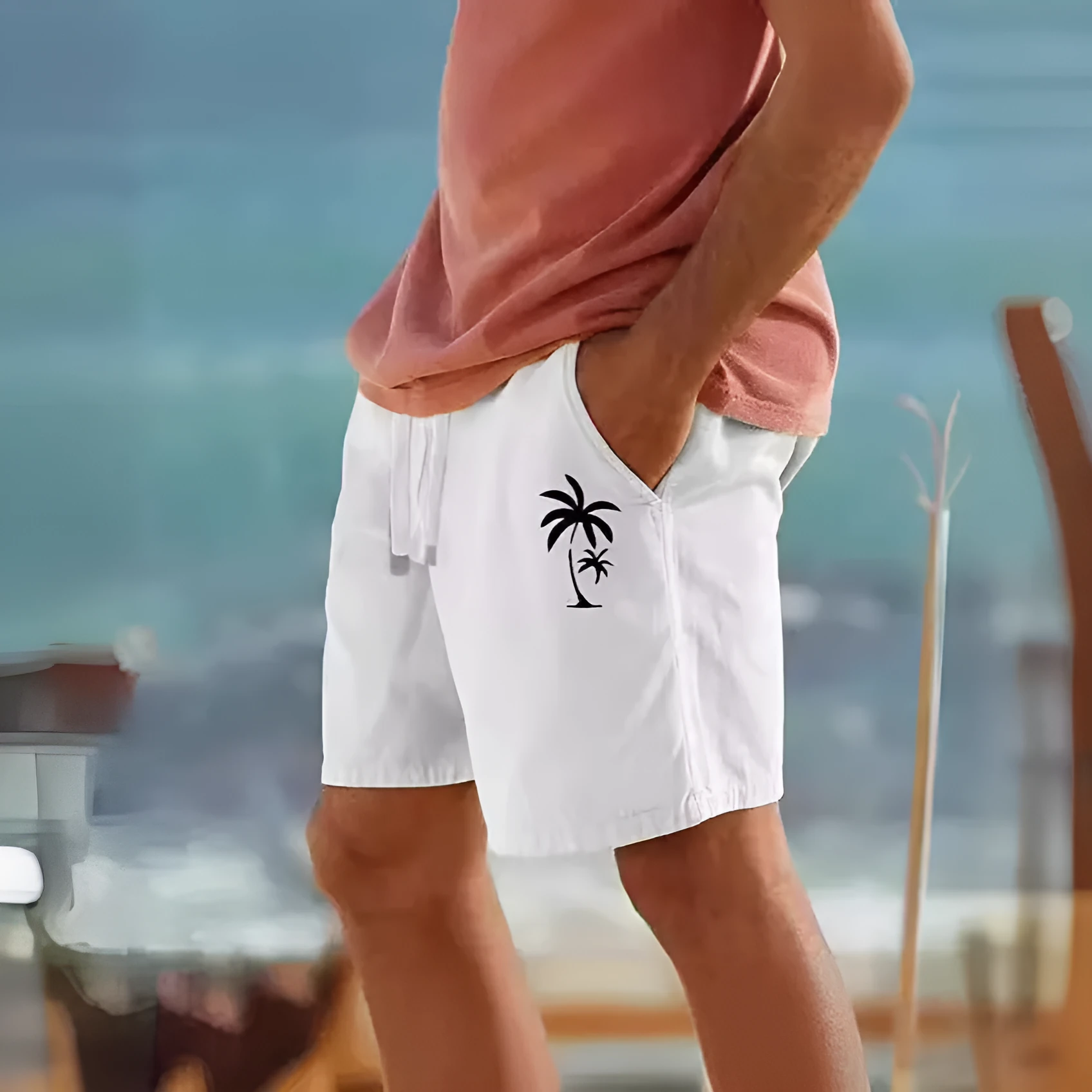 Men's beige shorts with green leaf print, featuring an elastic drawstring waistband.