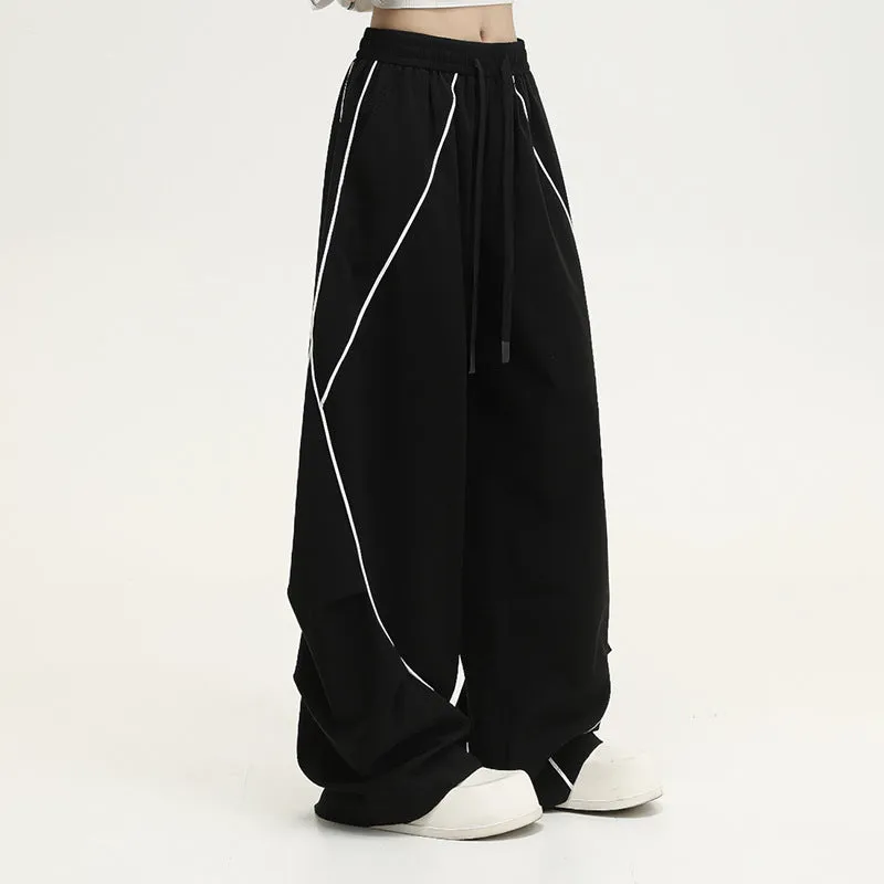 Black striped pleated wide-leg hip hop trousers laid flat, showing loose fit and mid waist.