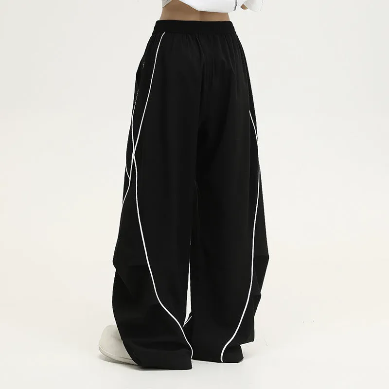 Black striped pleated wide-leg hip hop trousers laid flat, showing loose fit and mid waist.