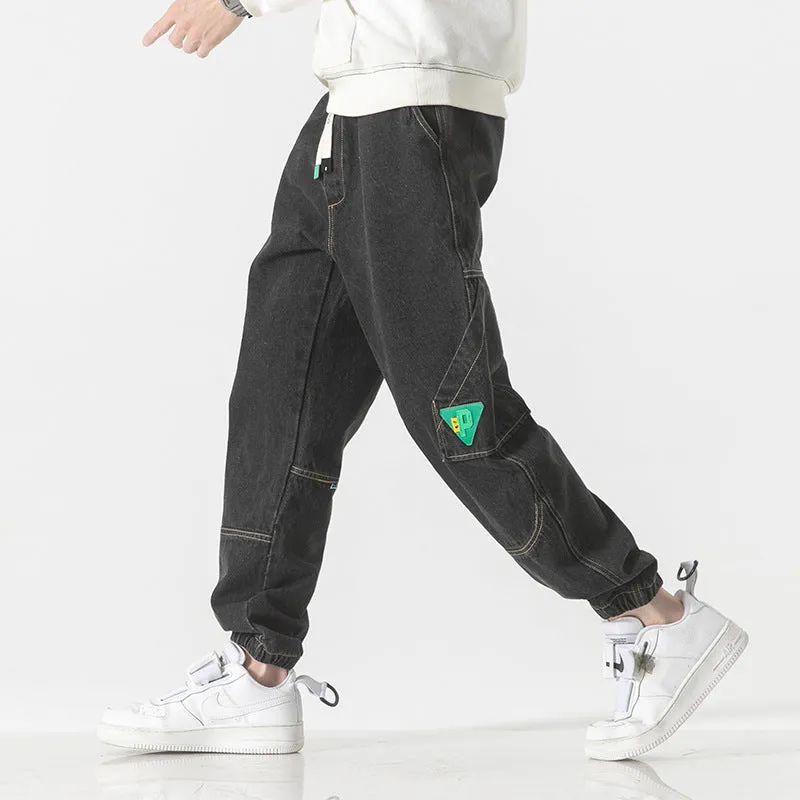 Men's black cotton loose-fit tapered trousers with a mid waist on a hanger.
