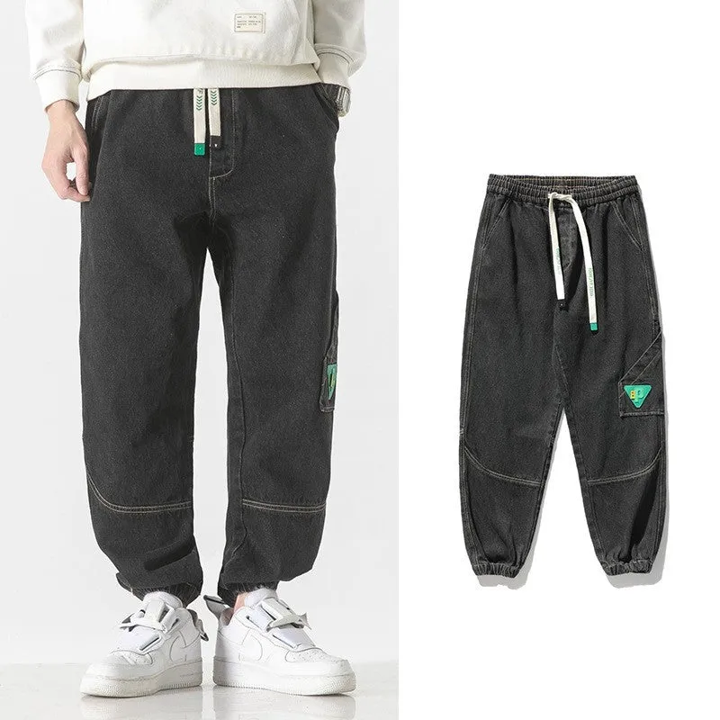 Men's black cotton loose-fit tapered trousers with a mid waist on a hanger.