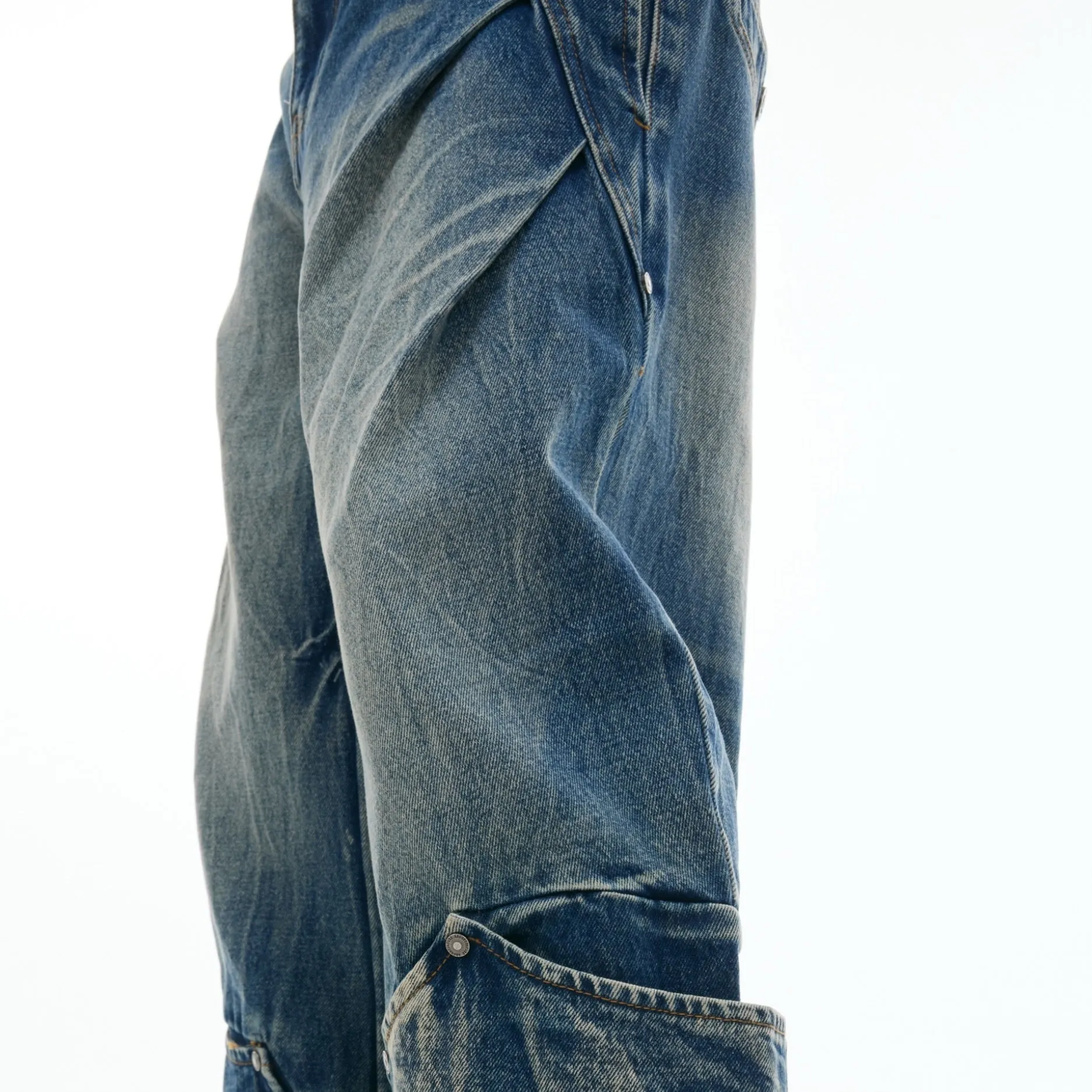 Man wearing verdant blue loose-fit retro jeans with a washed burst pattern.