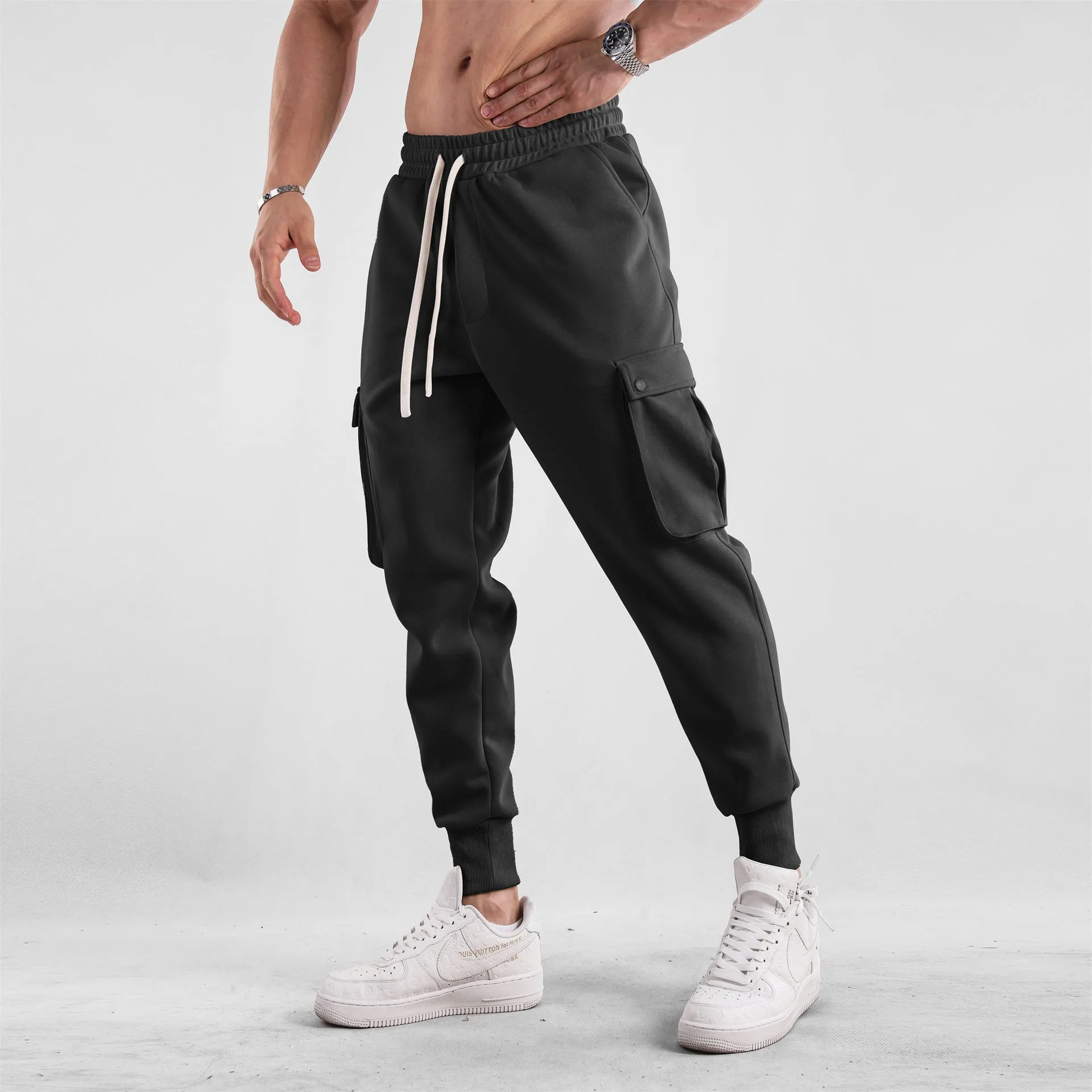 Men's loose light grey cotton trousers with ankle ties and multiple pockets laid flat.
