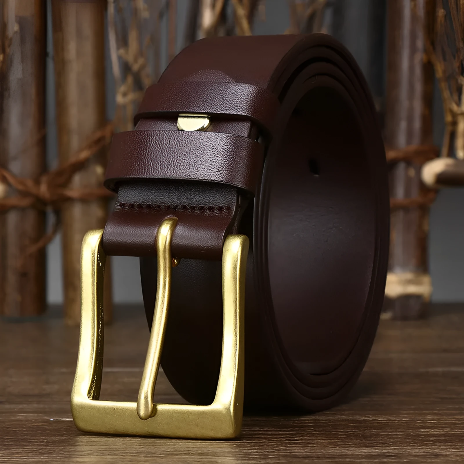 Men's brown leather belt with copper pin buckle on a plain background showing glossy first layer cowhide finish