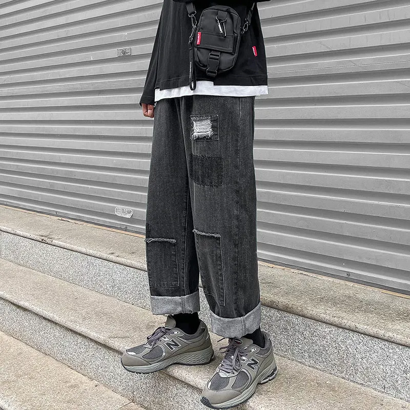 Men's high street ripped jeans with loose straight leg fit in black, showing rips on front thigh area