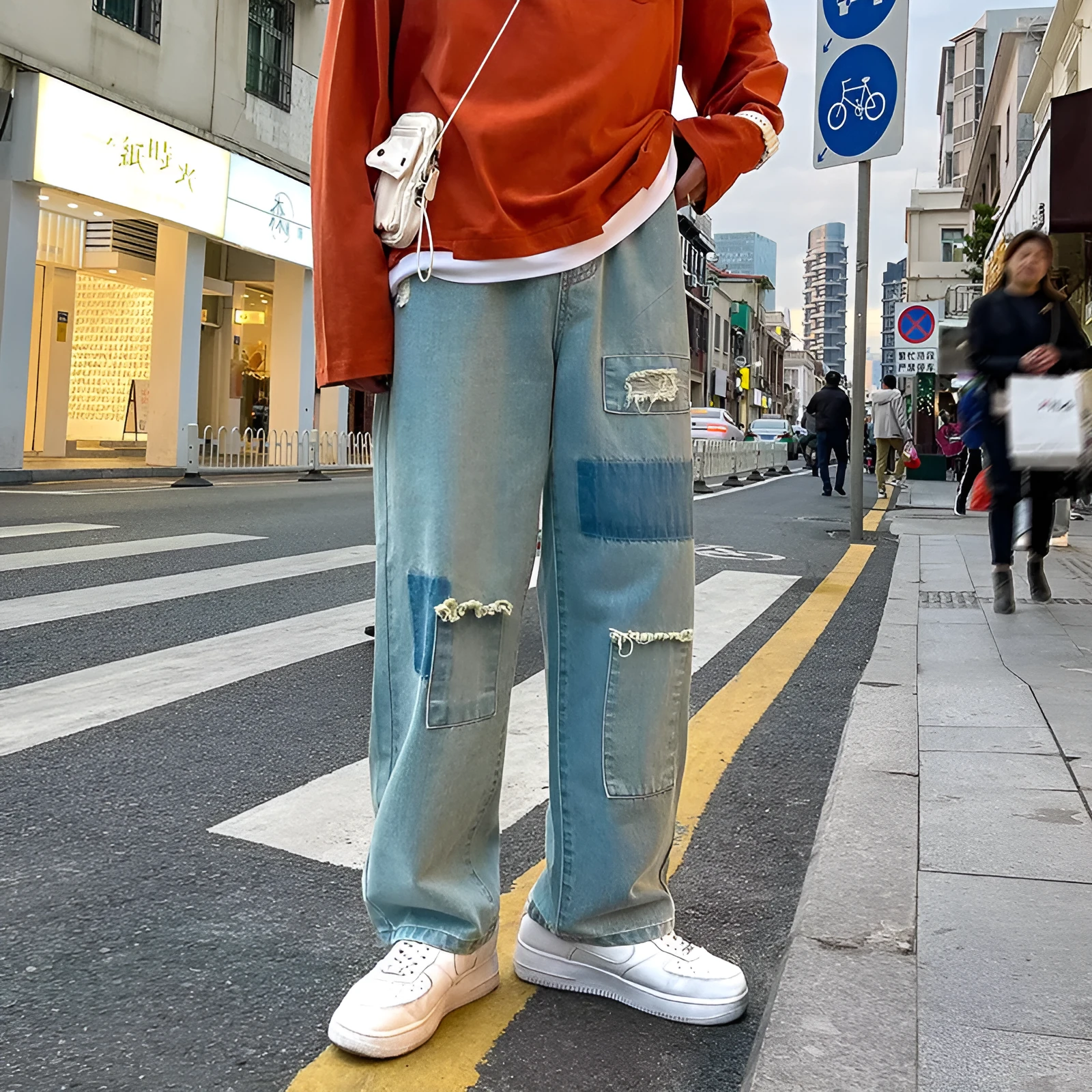 Men's high street ripped jeans with loose straight leg fit in black, showing rips on front thigh area