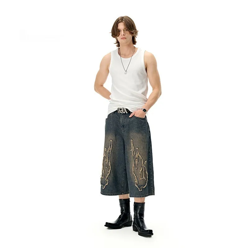 Men's black cropped denim shorts with orange flame embroidery patch on leg