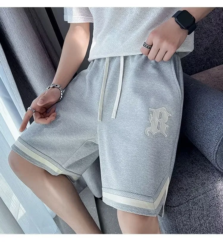 Men's loose straight drawstring sports shorts in solid colour with wide leg and low waist on plain background