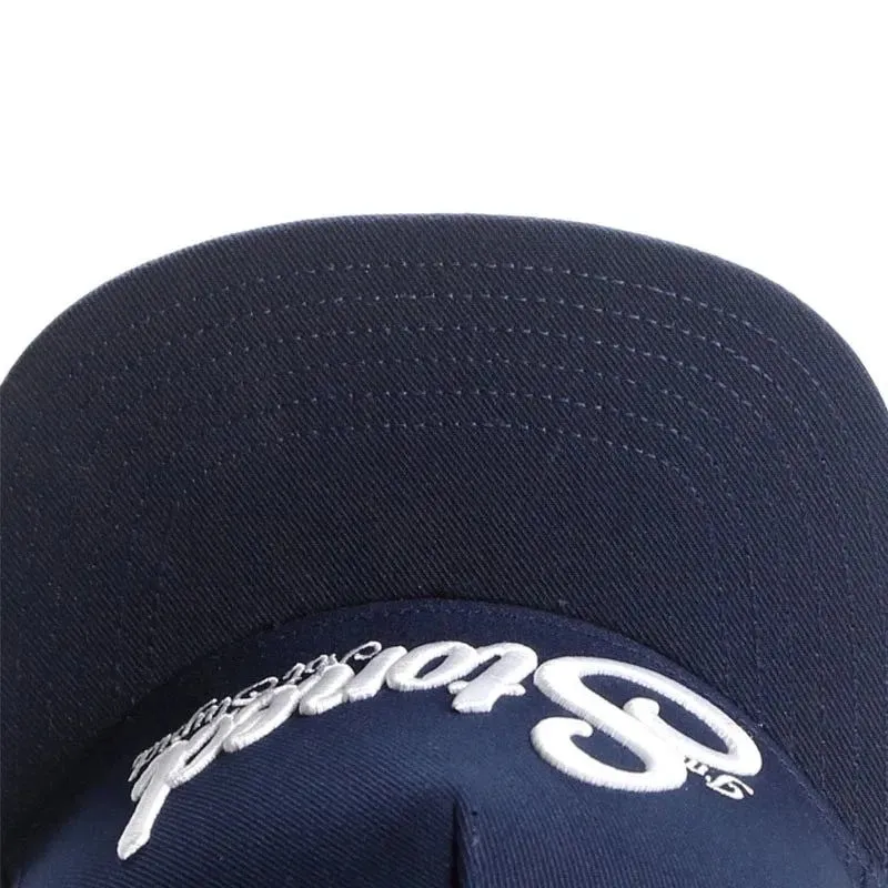 Navy blue cotton baseball cap with machine-embroidered English letters on front, dome crown, adjustable back strap