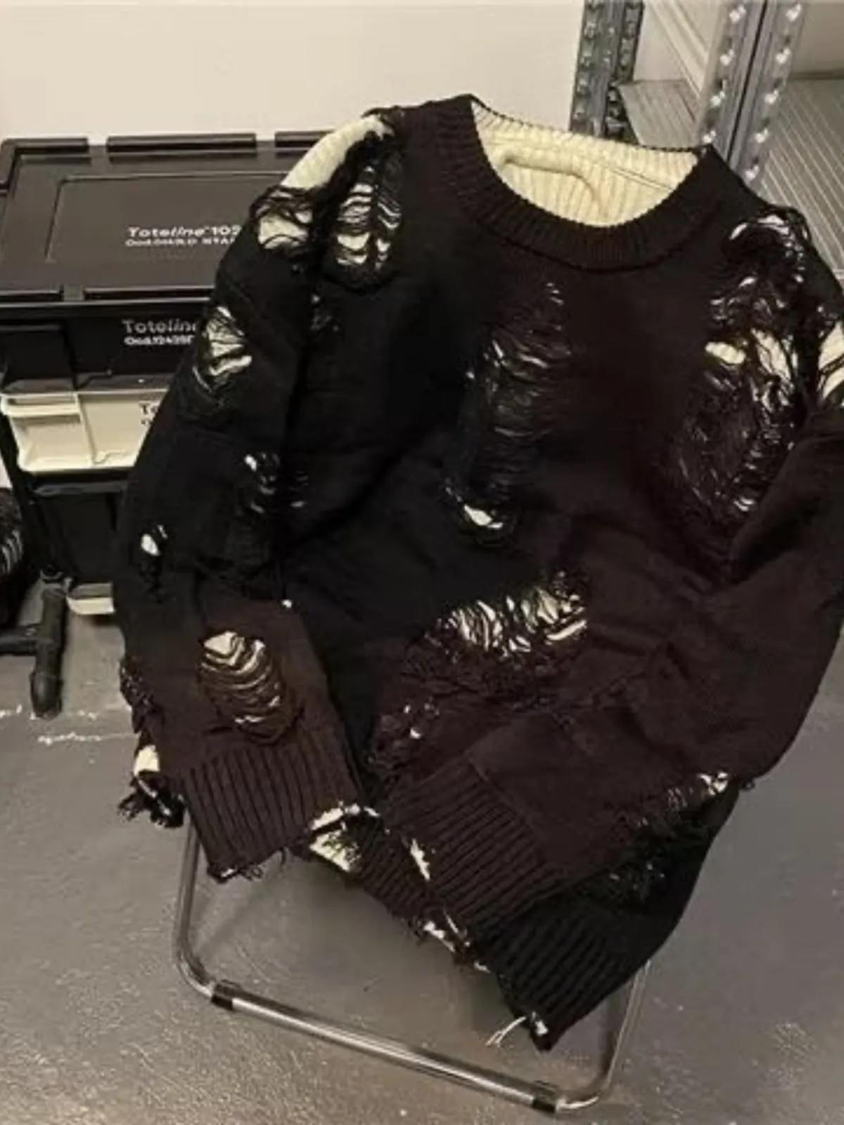 Men's black ripped pullover sweater with animal pattern and tassels on gray background