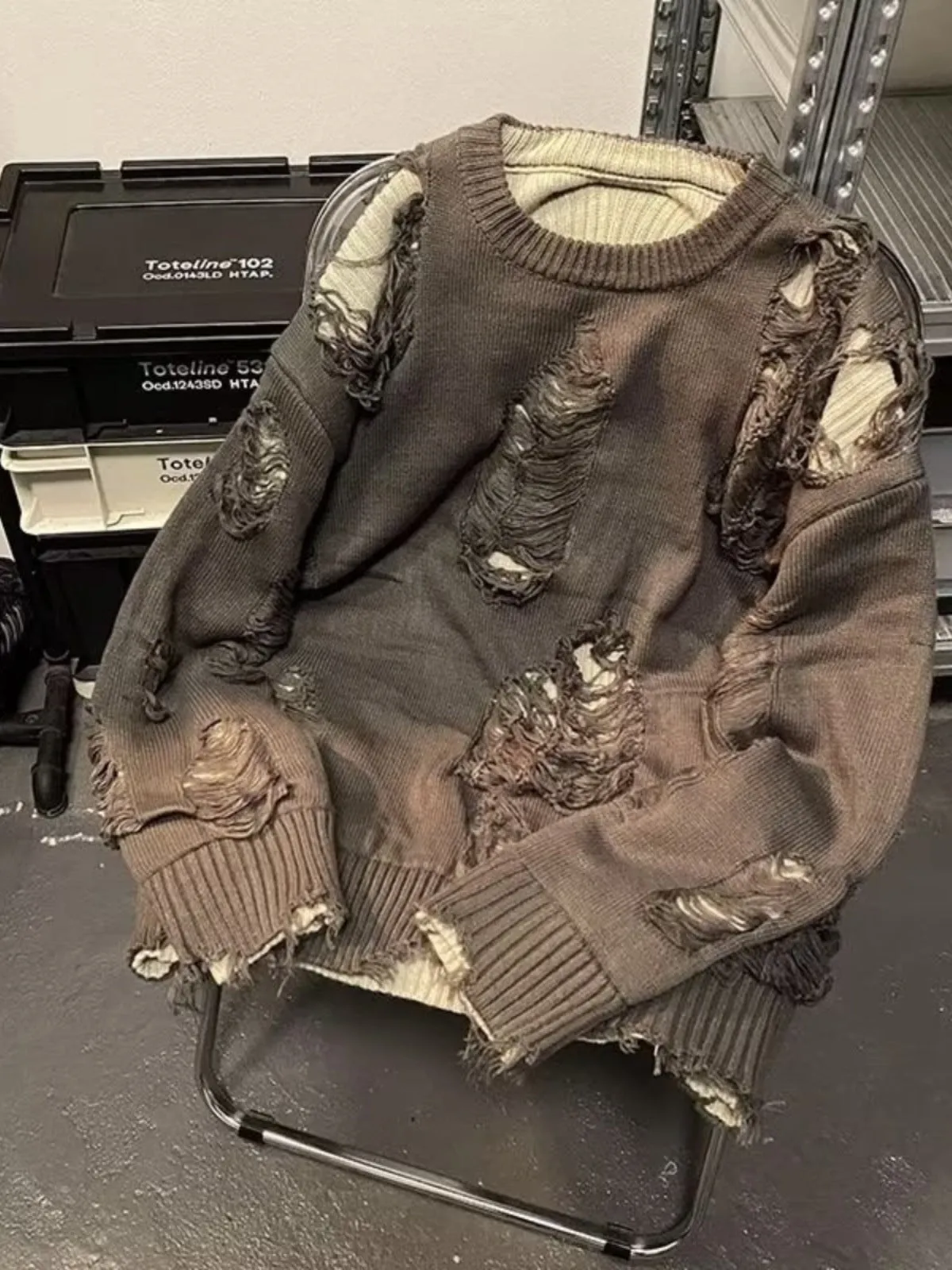 Men's black ripped pullover sweater with animal pattern and tassels on gray background