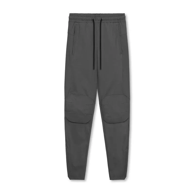 Man wearing loose grey running trousers with tied ankles, made from quick-dry polyester fabric.