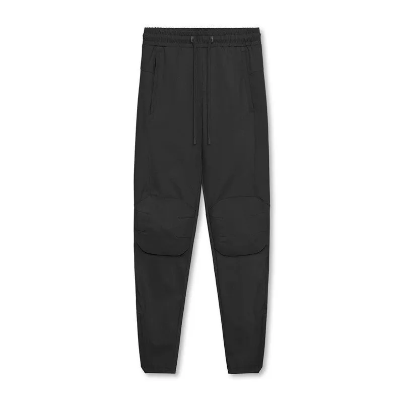 Man wearing loose grey running trousers with tied ankles, made from quick-dry polyester fabric.