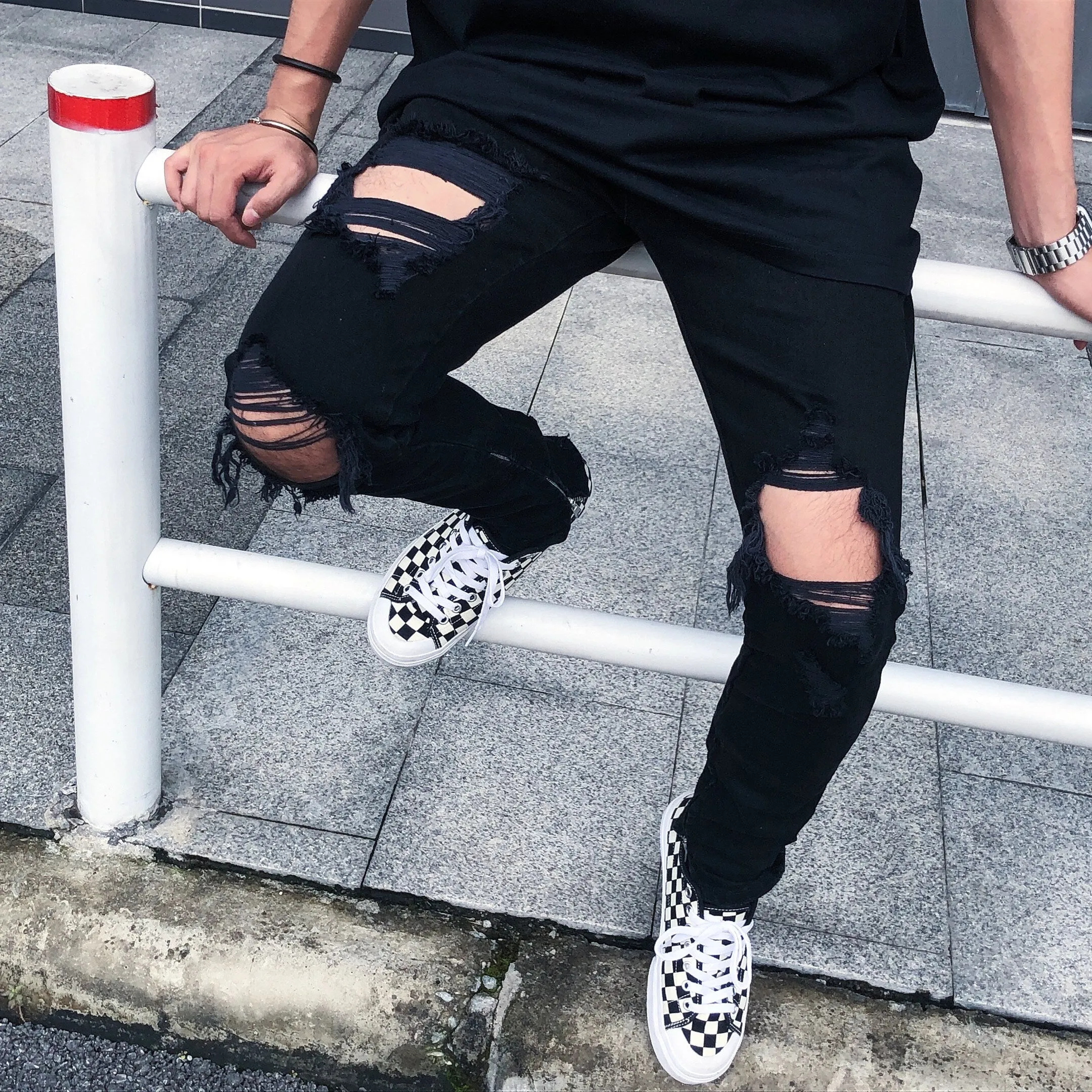 Men's high street style black torn jeans in washed black denim with raw edge details, front view.