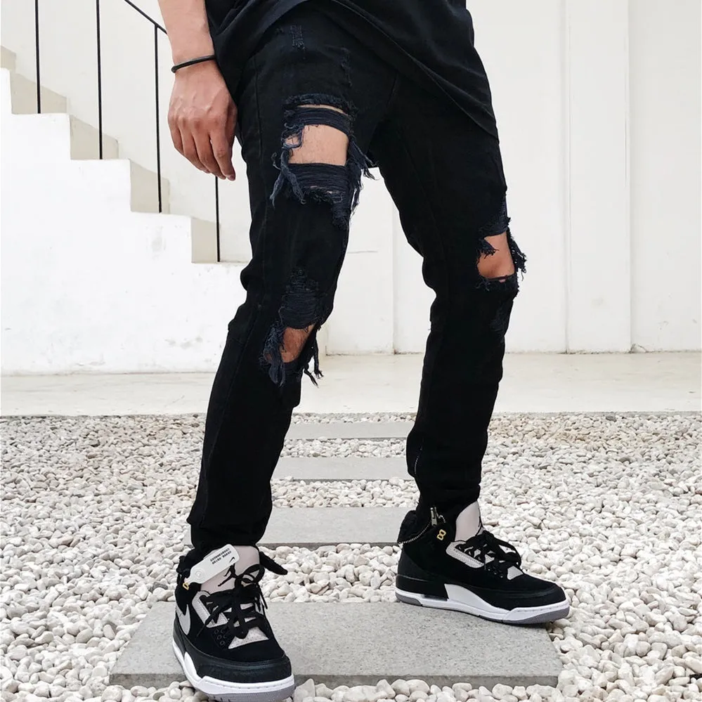 Men's high street style black torn jeans in washed black denim with raw edge details, front view.