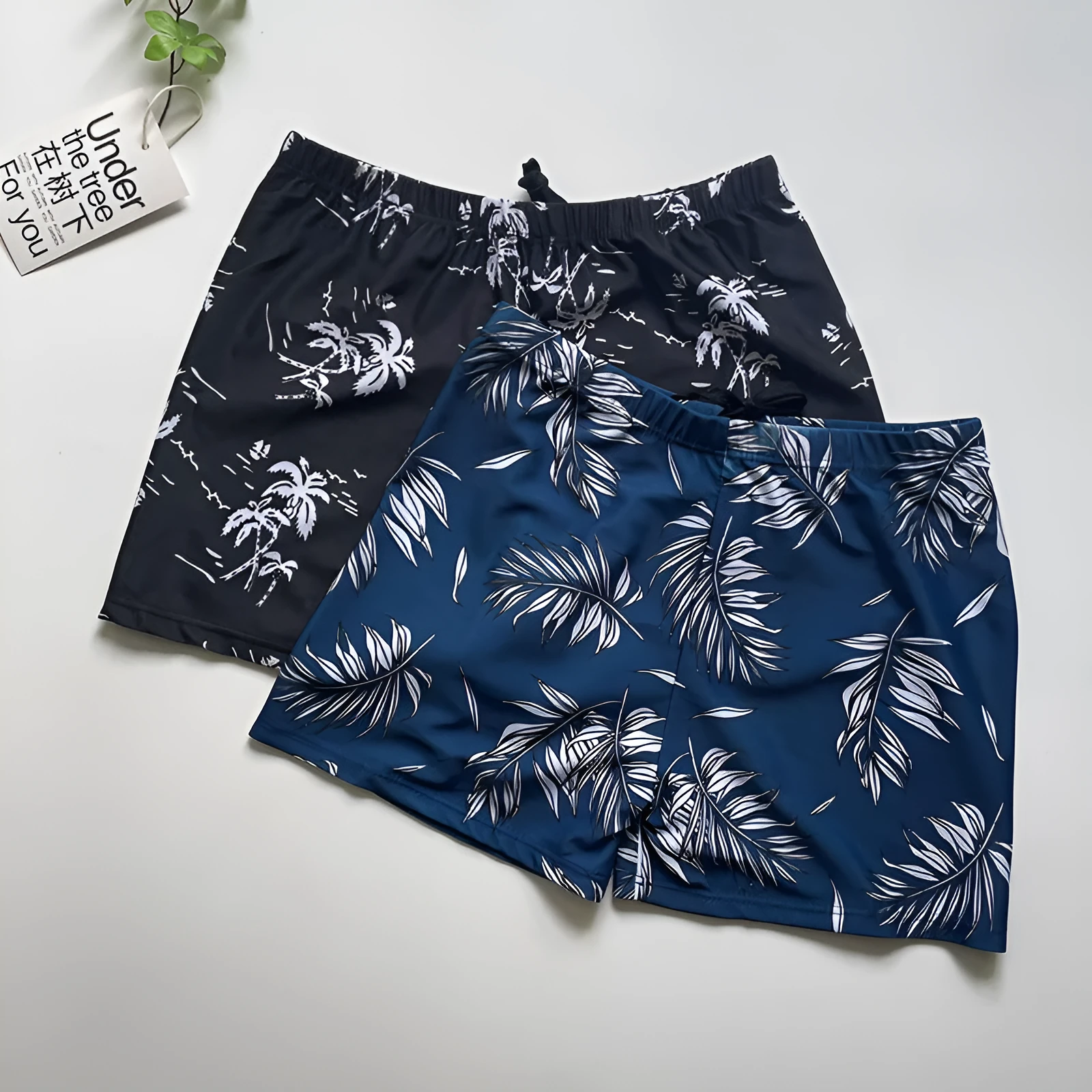 Men's loose-fit polyester swim trunks in dark blue with large flower print, three sizes available