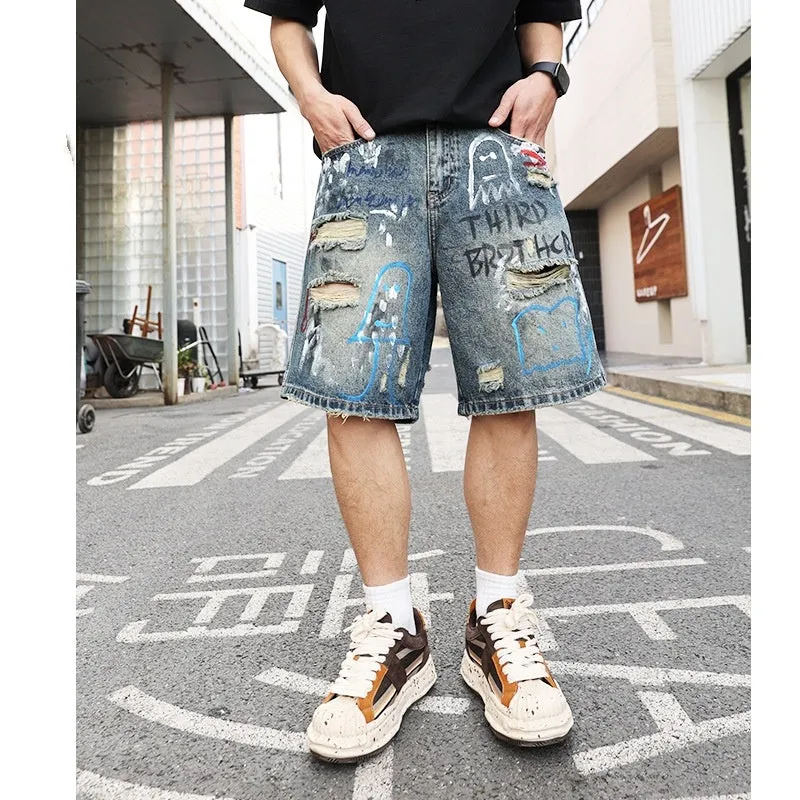 Blue men's ripped denim shorts with graffiti style and straight leg cut on a hanger.