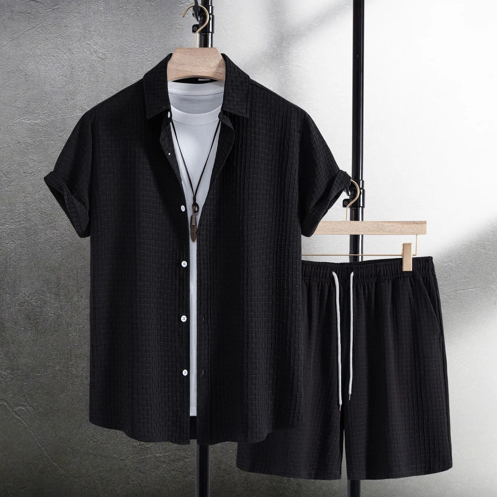 Men's black cotton blend short sleeve shirt and shorts beach suit laid flat.