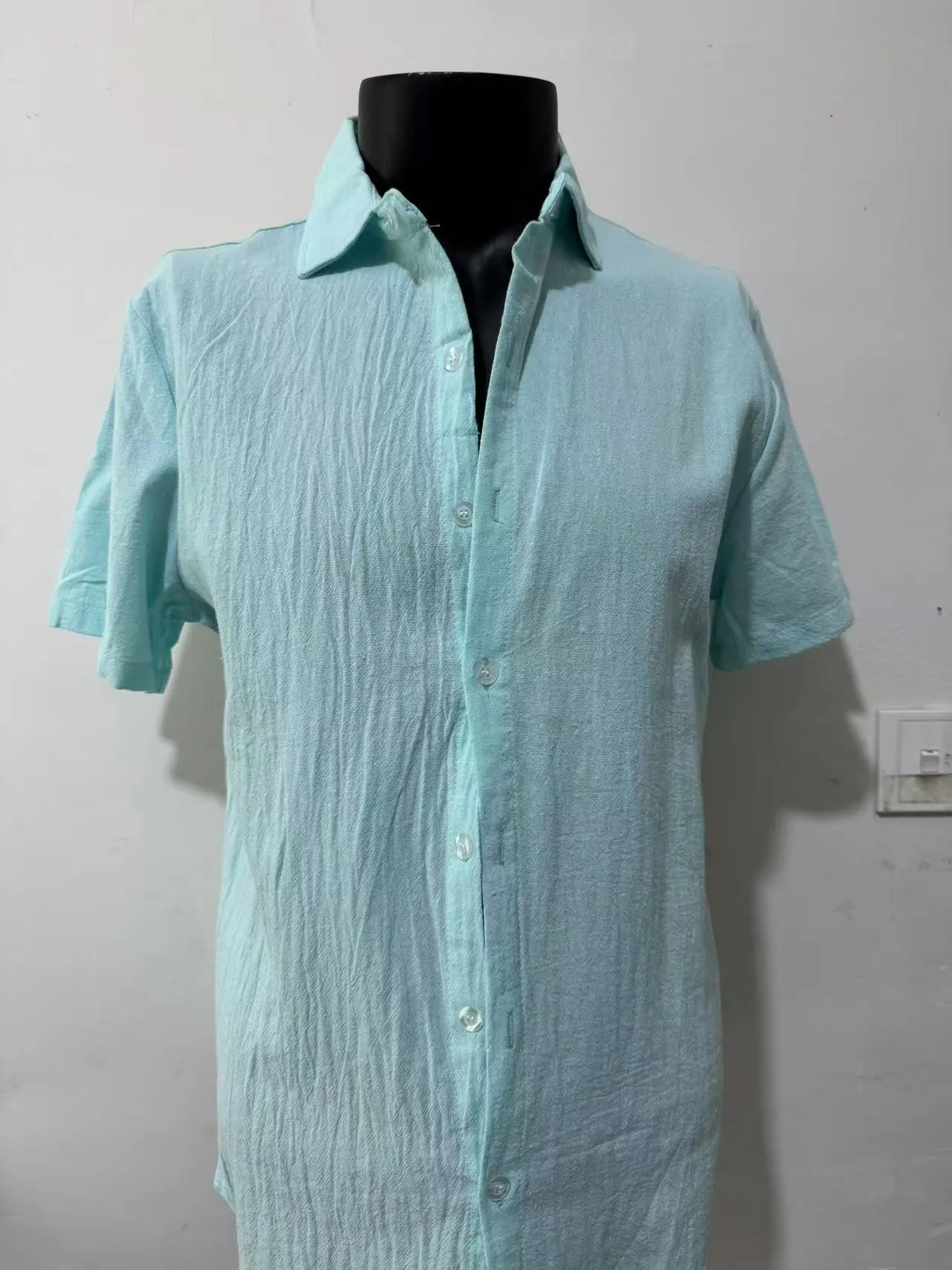 Men's solid colour short sleeve linen blend shirt on a hanger, showing loose fit.