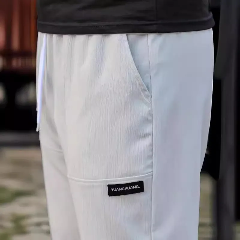 Men's light grey polyester trousers for spring and autumn wear, laid flat.