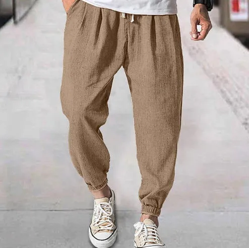 Man wearing loose light-coloured cotton trousers with elasticated ankle cuffs, showing front and side views.