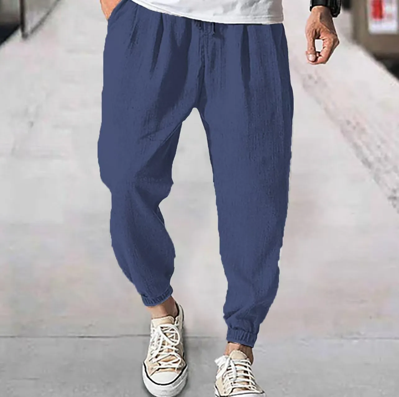 Man wearing loose light-coloured cotton trousers with elasticated ankle cuffs, showing front and side views.