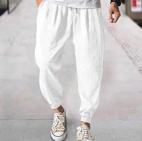 Man wearing loose light-coloured cotton trousers with elasticated ankle cuffs, showing front and side views.