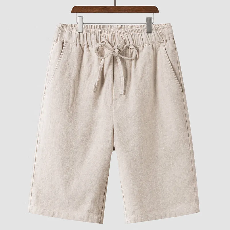 Pair of beige men's casual linen shorts with a loose fit and cropped length on a plain background.