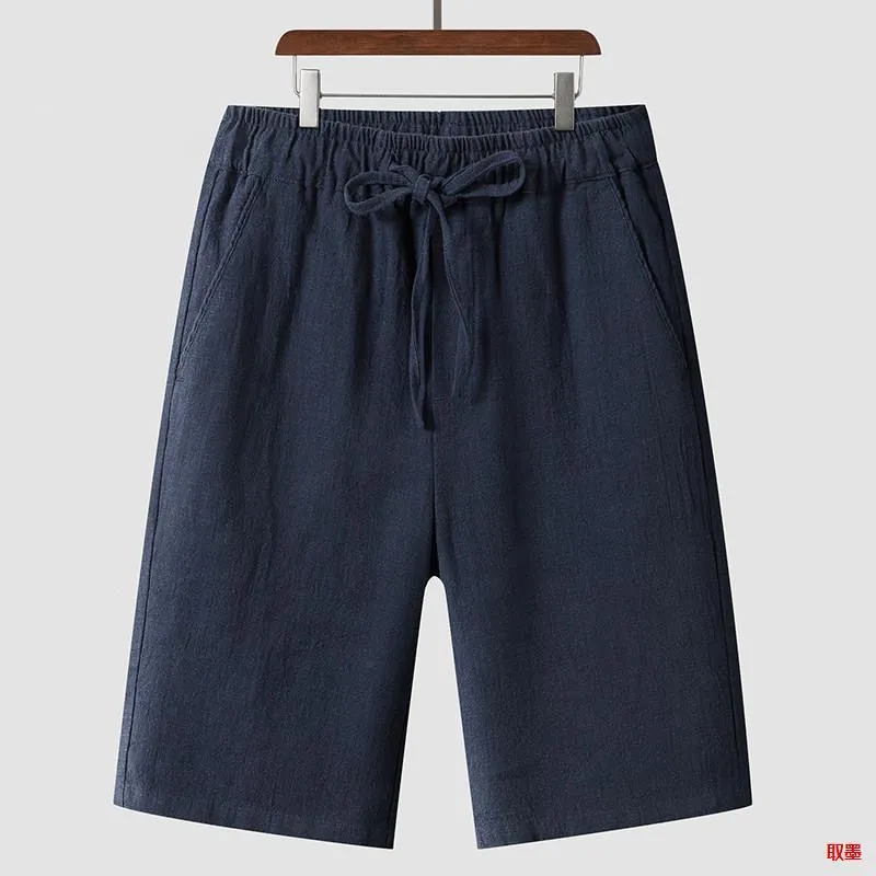 Pair of beige men's casual linen shorts with a loose fit and cropped length on a plain background.