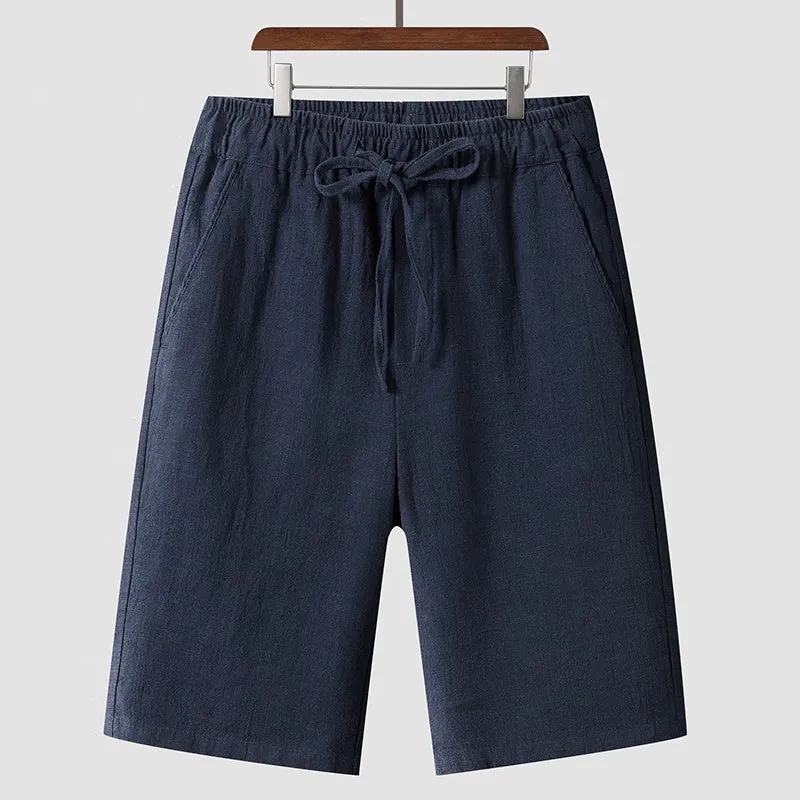 Pair of beige men's casual linen shorts with a loose fit and cropped length on a plain background.