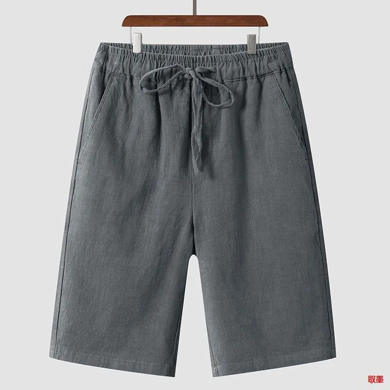 Pair of beige men's casual linen shorts with a loose fit and cropped length on a plain background.