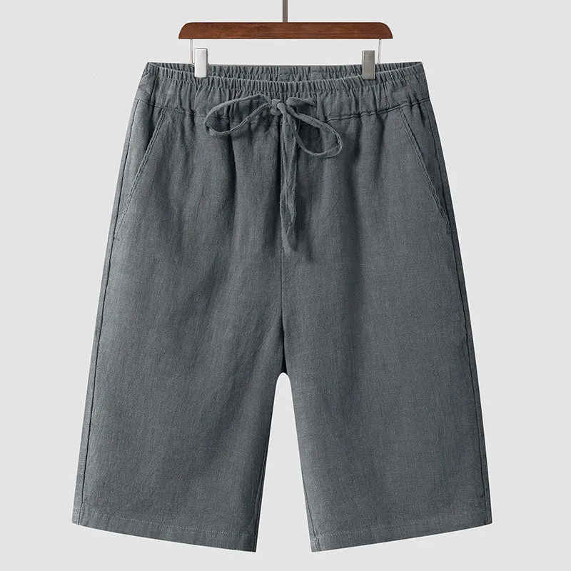 Pair of beige men's casual linen shorts with a loose fit and cropped length on a plain background.