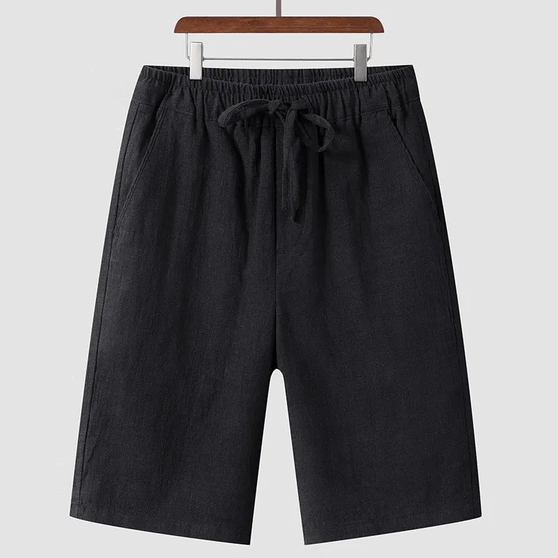 Pair of beige men's casual linen shorts with a loose fit and cropped length on a plain background.