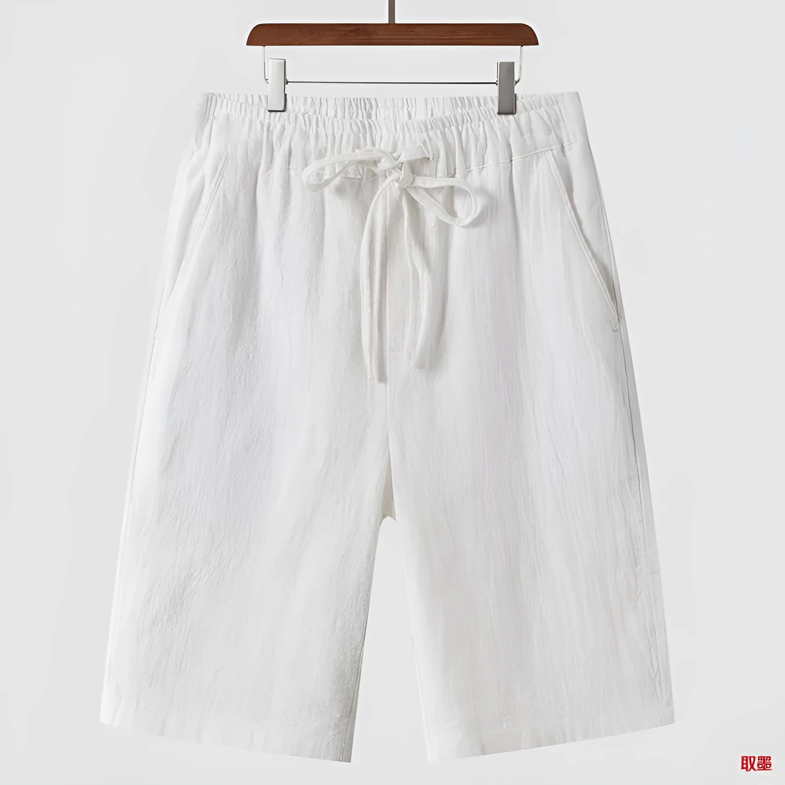 Pair of beige men's casual linen shorts with a loose fit and cropped length on a plain background.